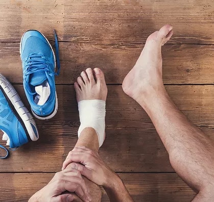 Image of an injured foot with the left ankle wrapped in a white bandage