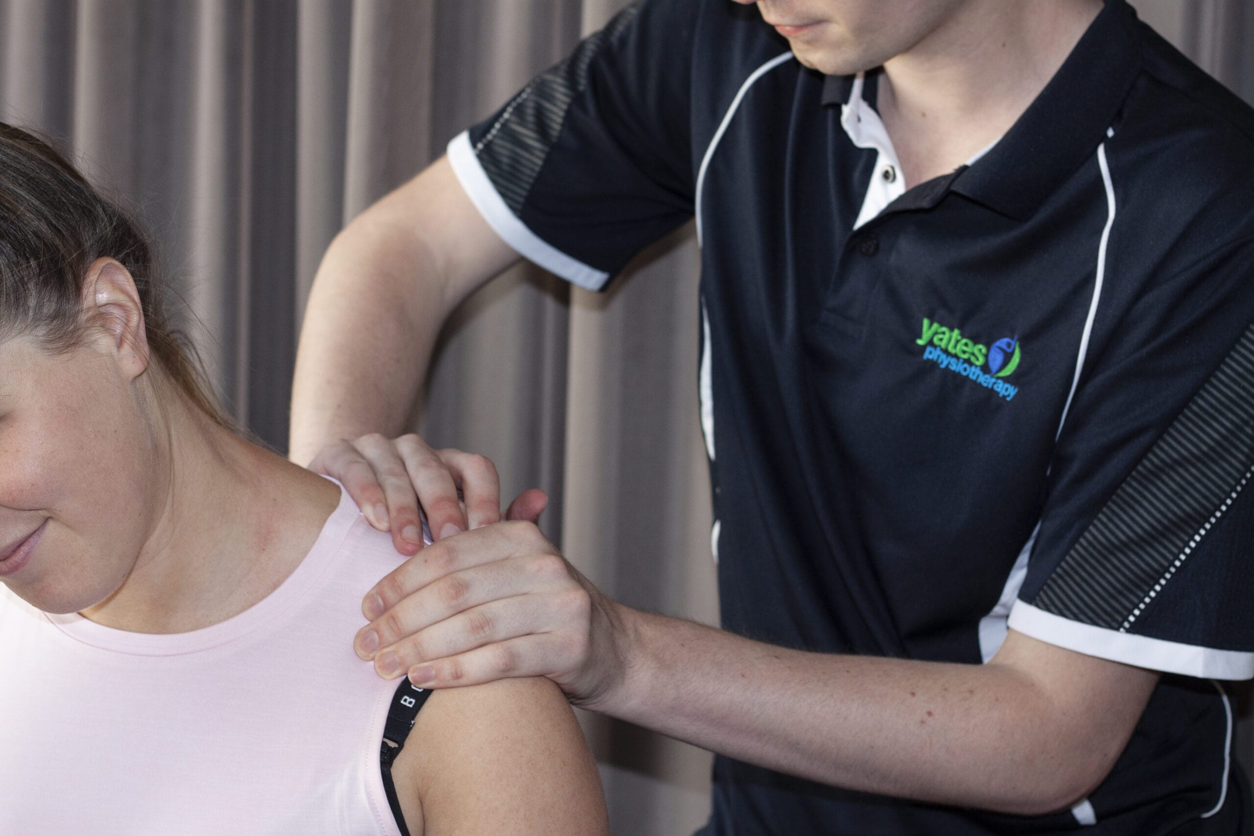 A woman receiving remedial massage on her shoulder from a massage therapist.