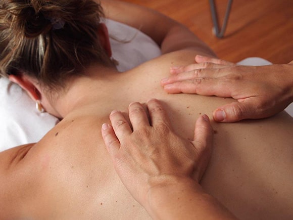 A woman receiving a back massage from a massage therapist.