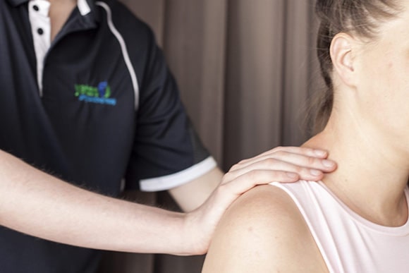 A woman receiving a shoulder massage from a massage therapist.