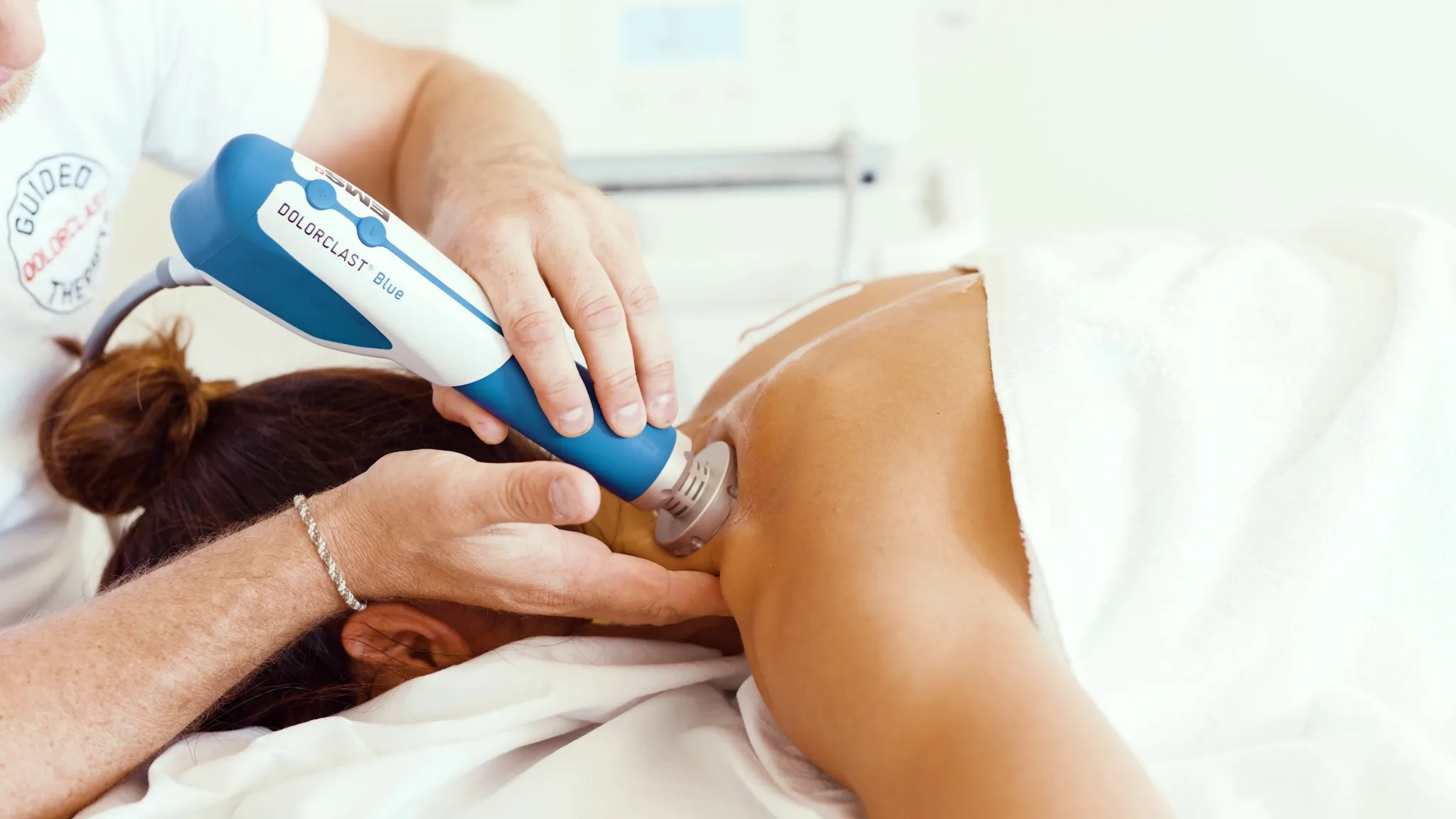 Physiotherapist performing shockwave therapy on a patient’s shoulder for pain relief, pain management, and to decrease pain naturally.